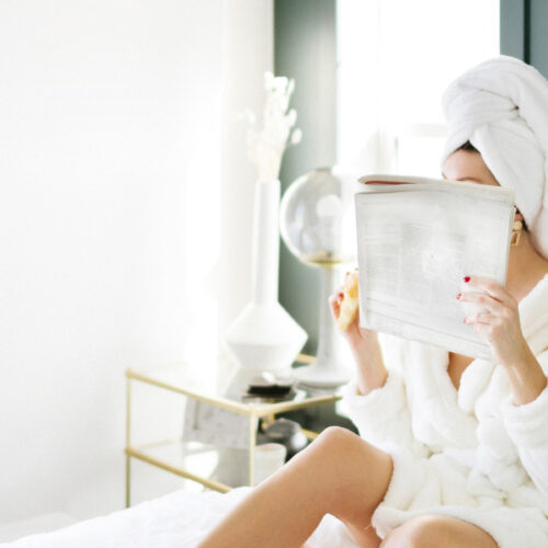 woman practicing self care drinking tea and reading a book