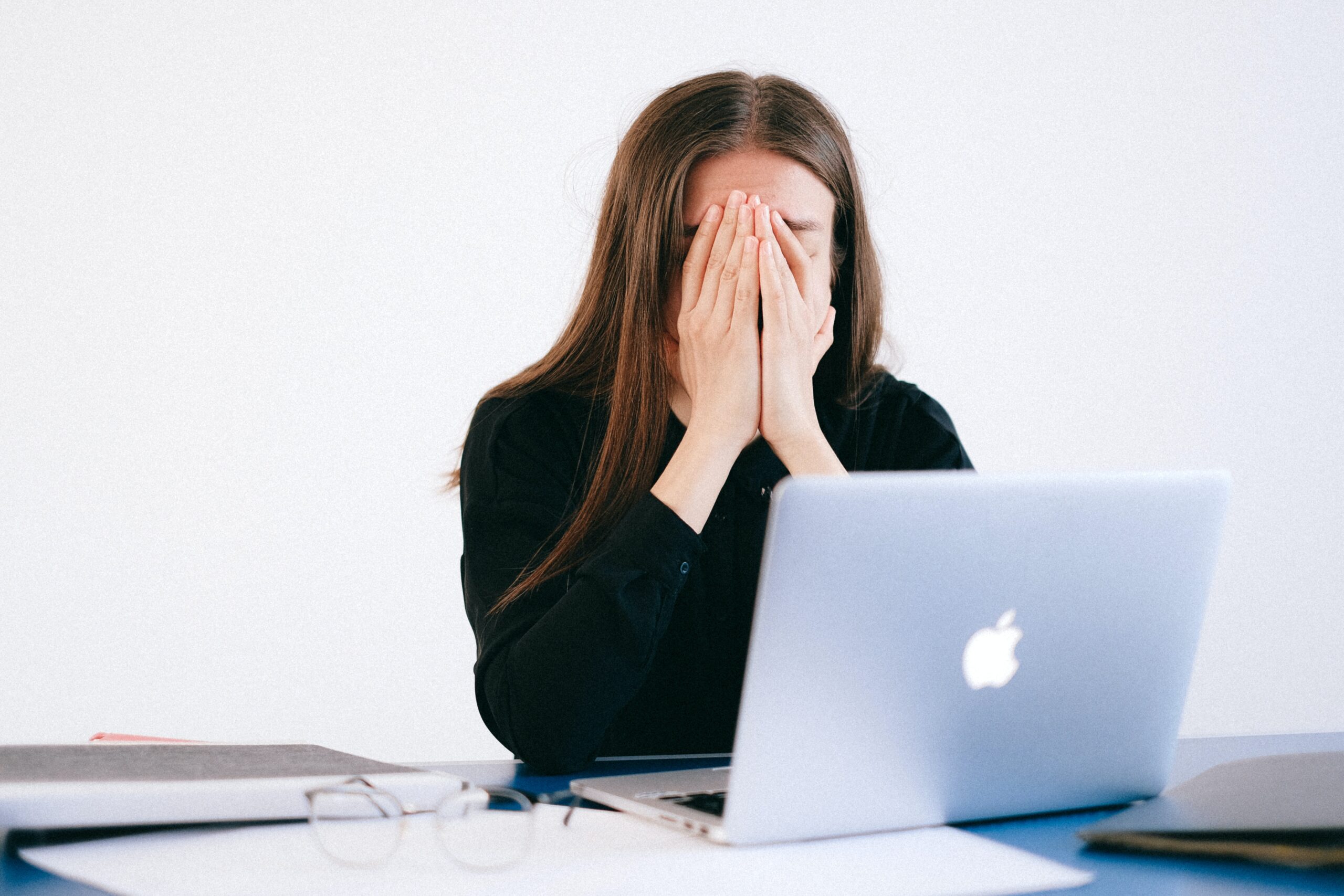 woman working on her laptop with hands covering her face
