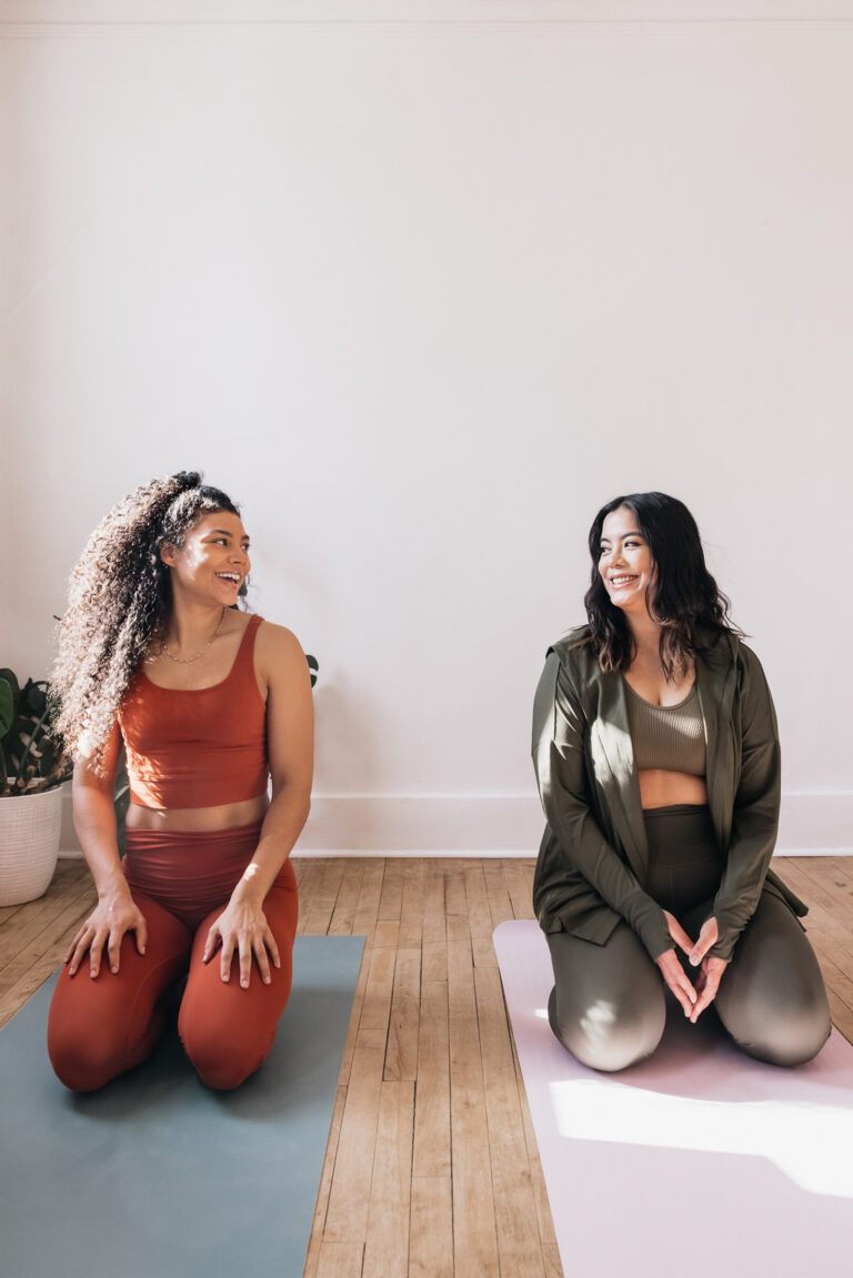 two women sitting on yoga mats