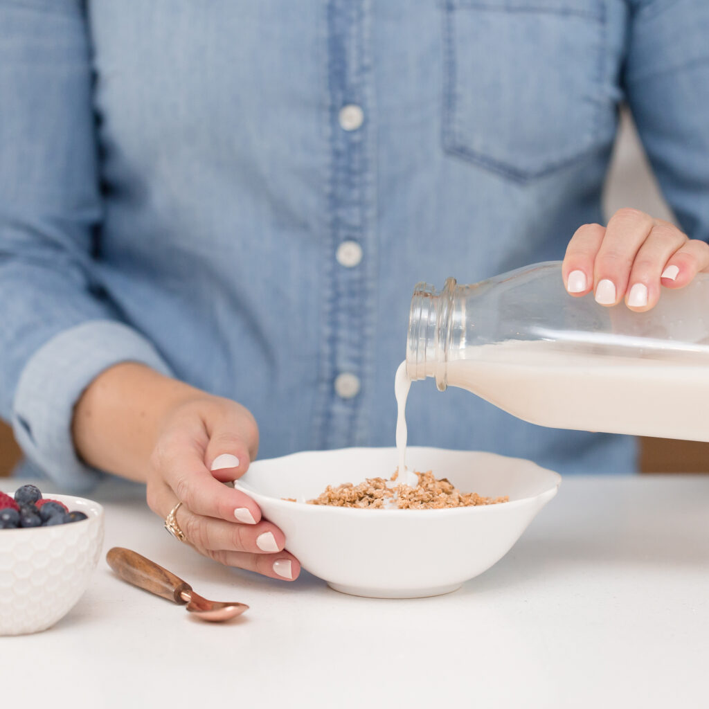 woman pouring oat milk into her cereal
