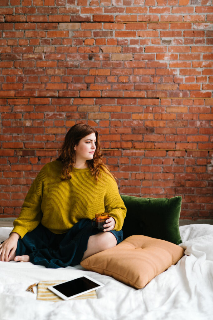 woman sitting on bed thinking about to improve self confidence