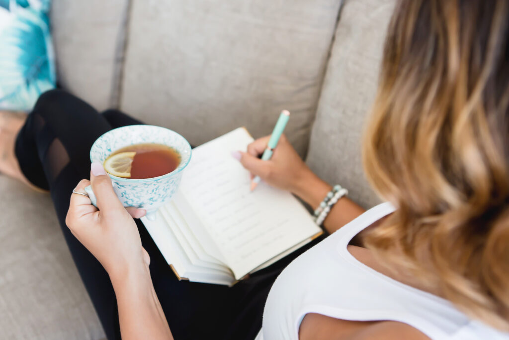 woman writing in journal and drinking tea