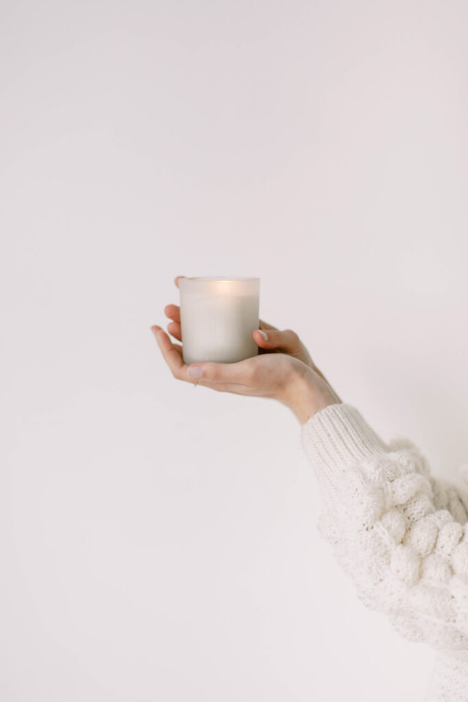 woman with beige sweater holding a candle