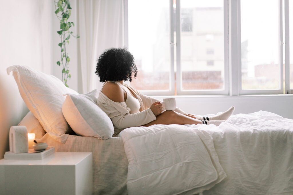 woman sitting on bed looking out the window